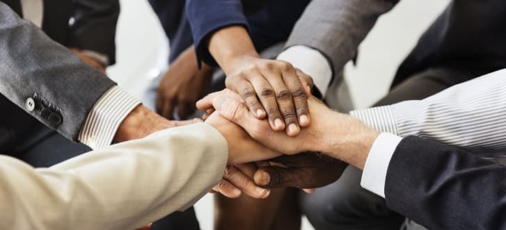 Diverse professionals joining hands in a show of partnership